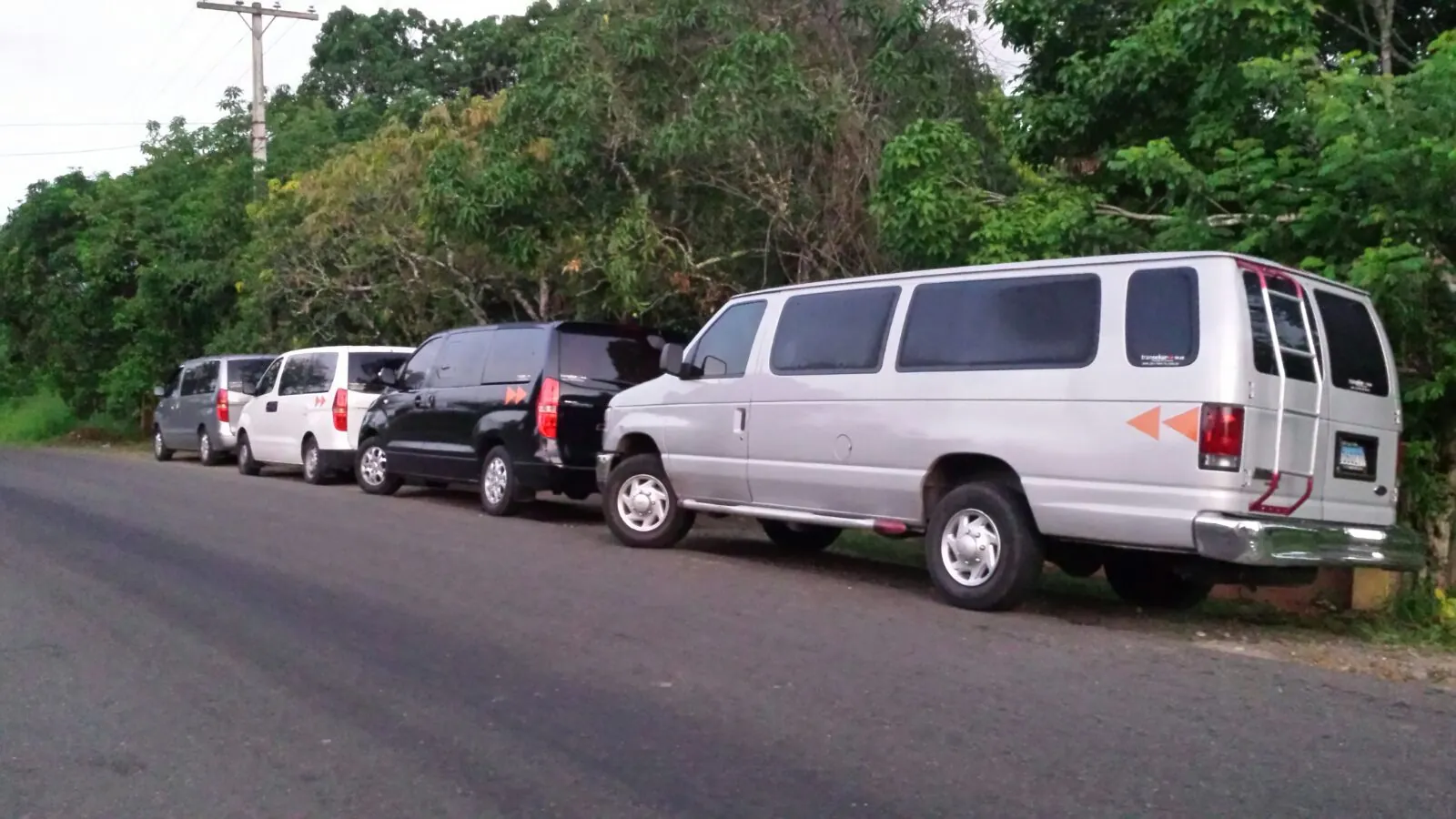 Colonne de SUV et de véhicules de transport de personnes alignés sur une route de campagne pendant un déplacement de production