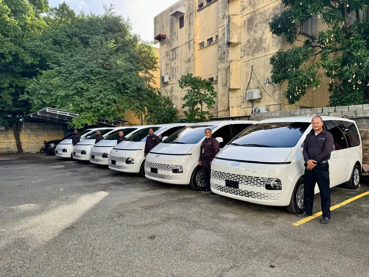 Seven Hyundai Staria vans lined up with uniformed Transekur chauffeurs