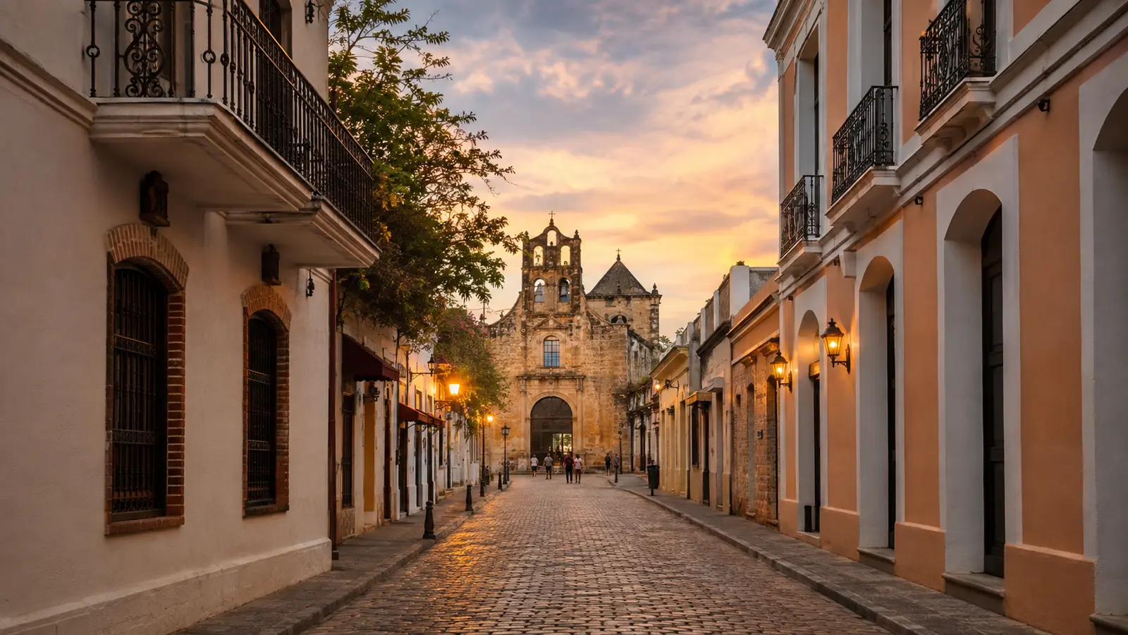 A cobblestone street of colonial buildings leading to a stone church at sunset in Santo Domingo