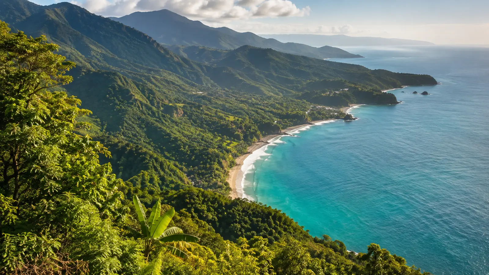 A green mountain coastline dropping to a curved sand beach and deep blue sea in the Dominican Republic