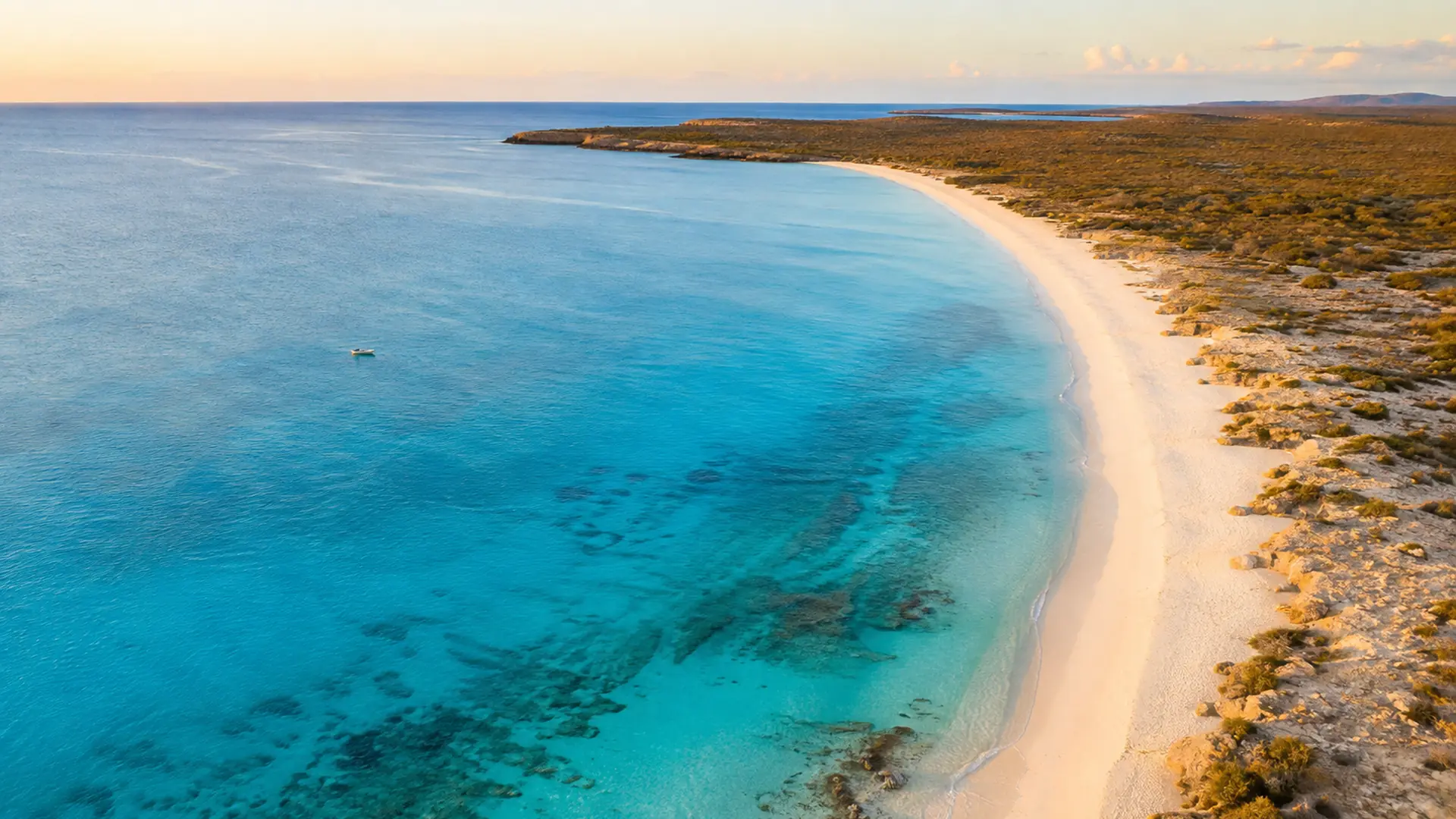Aerial view of the long empty sand curve and clear blue water of Bahía de las Águilas in Pedernales