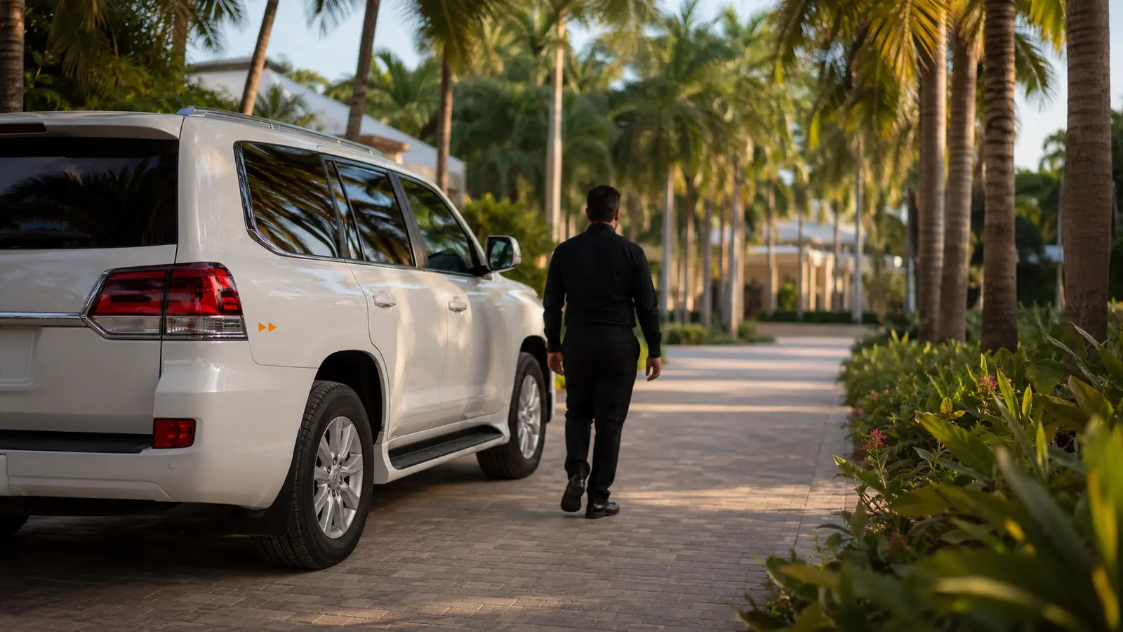 Travelers boarding a black chauffeured van at a lit resort arrival portico in Punta Cana at dusk
